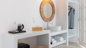 Un bagno moderno con uno specchio rotondo, un lavandino bianco e un portasciugamani.