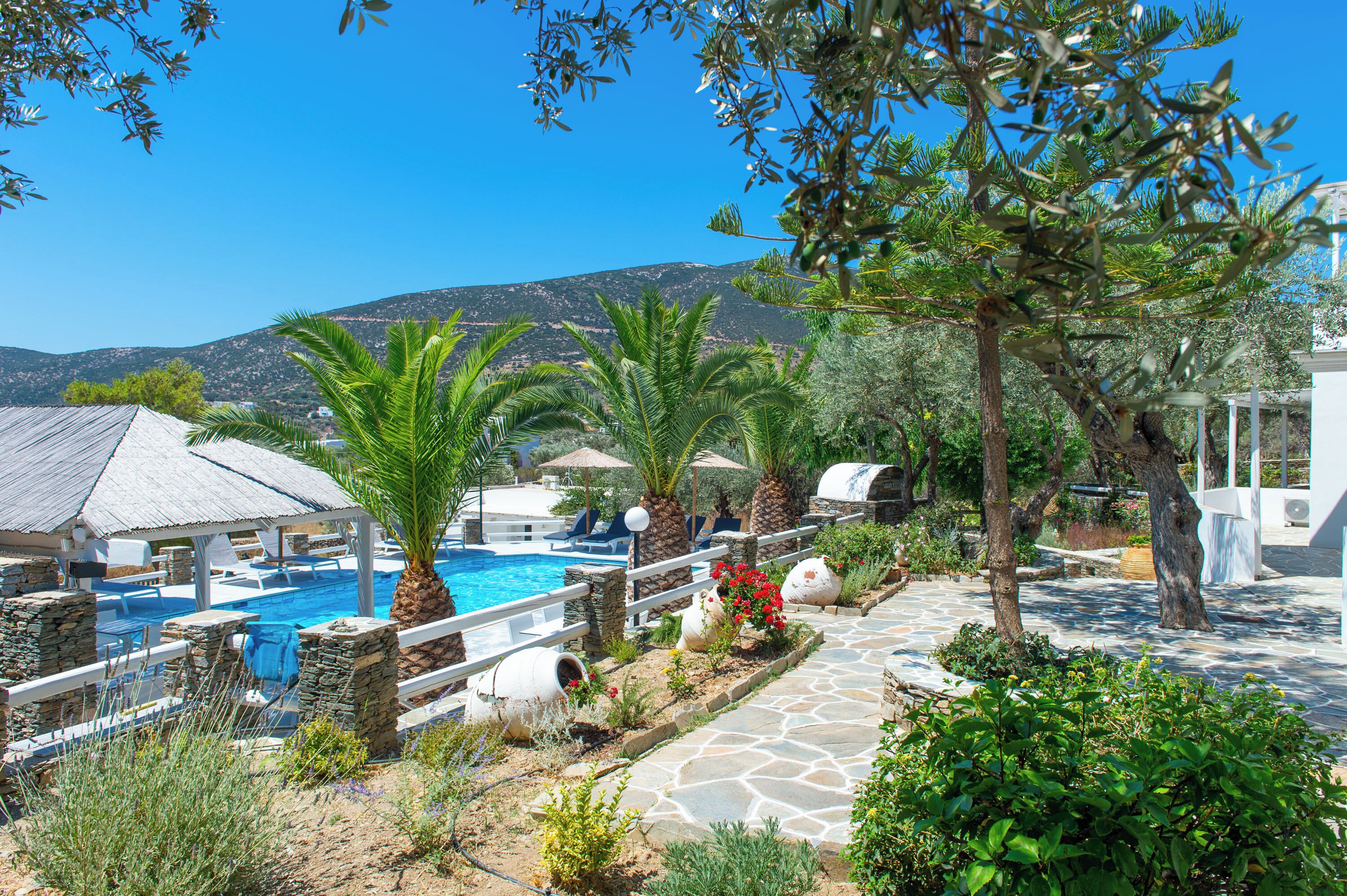 Zona de piscina amb gandules, un camí de pedra i vista a una muntanya.