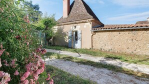 A building with a stone facade, a tiled roof, and a gravel path leading to a door. - Maison des hôtes – Dordogne: Charming Cottage for 4-5 Guests in Nature (Saint-Crépin-d'Auberoche)