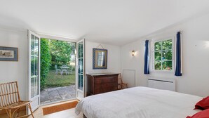 A bedroom with a bed, a dresser, a chair, and a window with curtains. - Maison des hôtes – Dordogne: Charming Cottage for 4-5 Guests in Nature (Saint-Crépin-d'Auberoche)