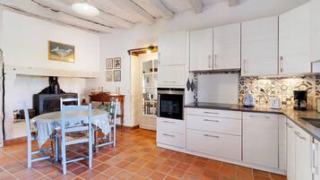 A kitchen with white cabinets, a dining table with chairs, and a tiled floor.