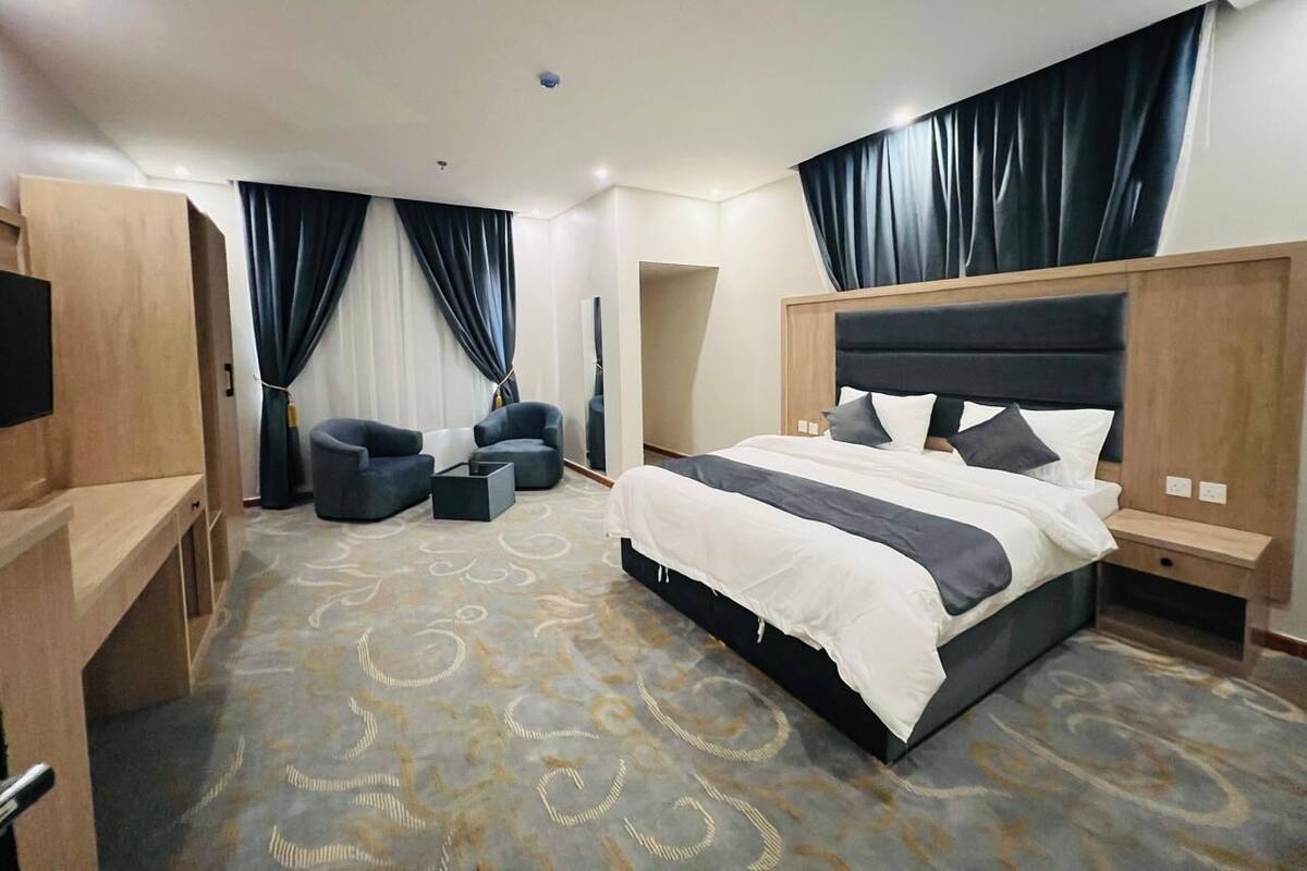 A modern hotel room with a large bed, a desk, a chair, and a TV.