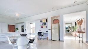Una cocina moderna con armarios blancos, un comedor con sillas blancas y una isla central.