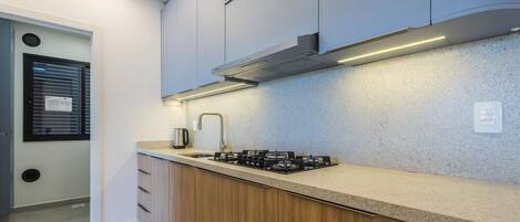 Una cocina moderna con estufa a gas, gabinetes de madera y una campana extractora de acero inoxidable.