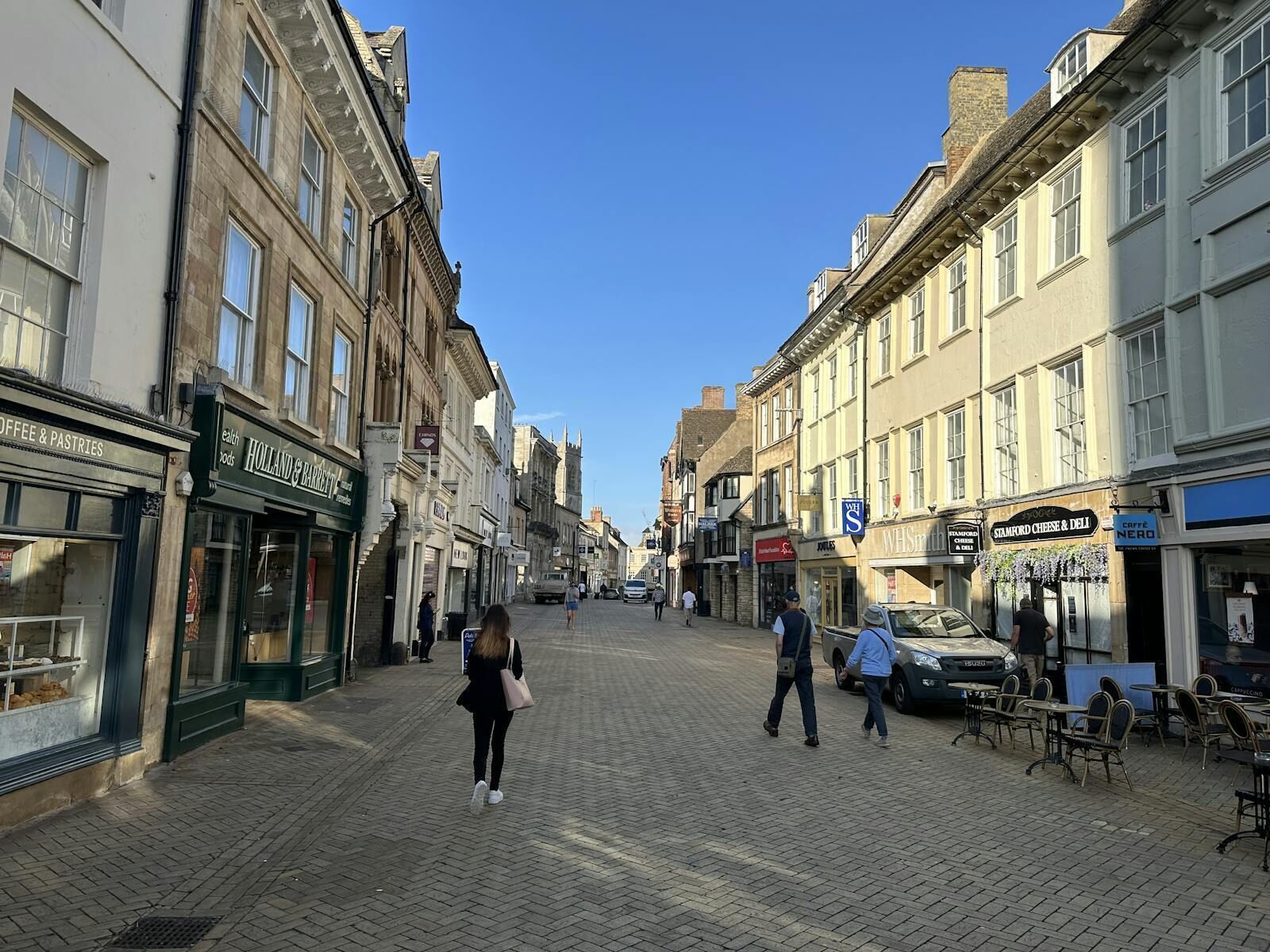 A pedestrian street lined with shops and cafes, featuring a variety of storefronts and outdoor seating areas.