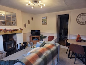 A cozy living room with a fireplace, a television, and a dining area. - Willow Wood (Settle)