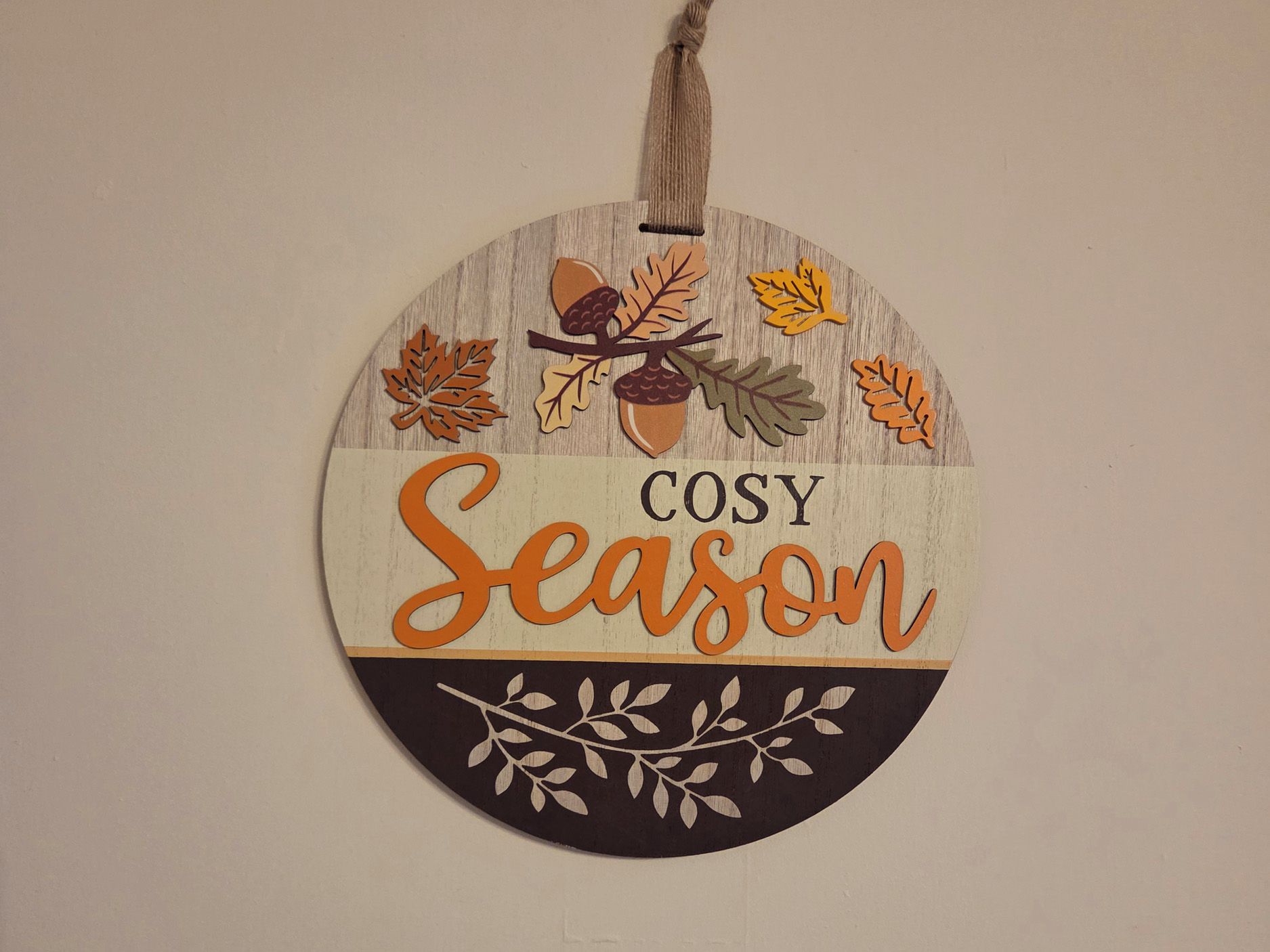Un panneau circulaire portant l’inscription « Saison COSY » et agrémenté de décorations sur le thème de l’automne.