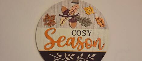 Un panneau circulaire portant l’inscription « Saison COSY » et agrémenté de décorations sur le thème de l’automne.