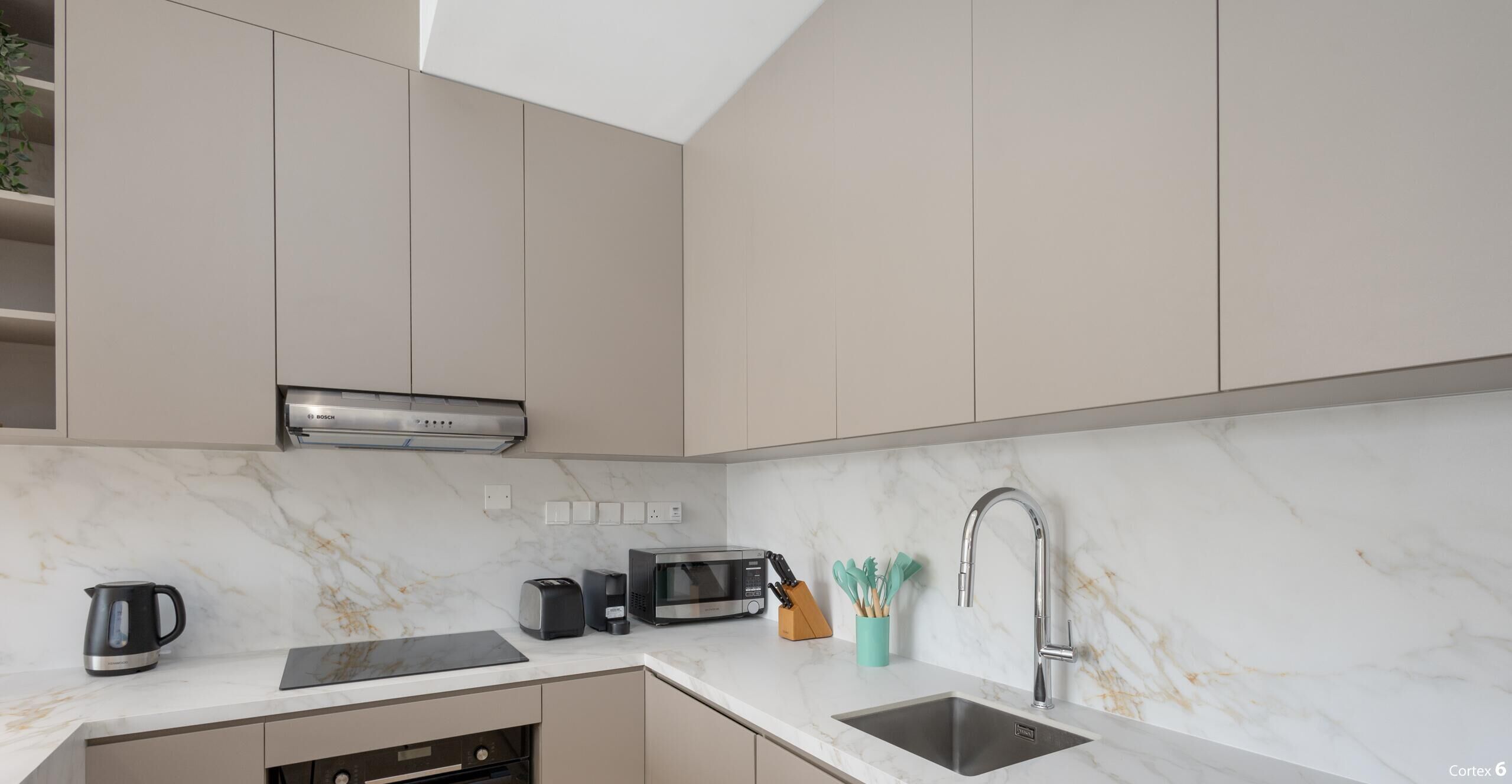 A modern kitchen with a Bosch microwave, toaster, and coffee maker on the counter, a sink with a modern faucet, and a Bosch range hood above the stove.