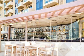 An outdoor bar area with wooden furniture and a hanging ceiling. - LUX The JW Marina Suite 5 (Dubai)