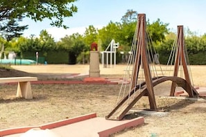 A playground with swings and a bench. - Mobile-home 6 persons air-conditioned camping 4* France (Cheval-Blanc)