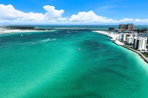 A coastal hotel with a marina, clear turquoise waters, and a bridge in the background. - Relaxing Destin Getaway Near Beaches & Attractions | Magnolia House 306 (Destin)