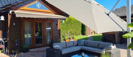 A house with a covered patio, a wooden exterior, and a large umbrella.
