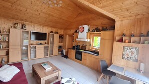 Un interior de madera con televisor, cocina, comedor y un sofá rojo.