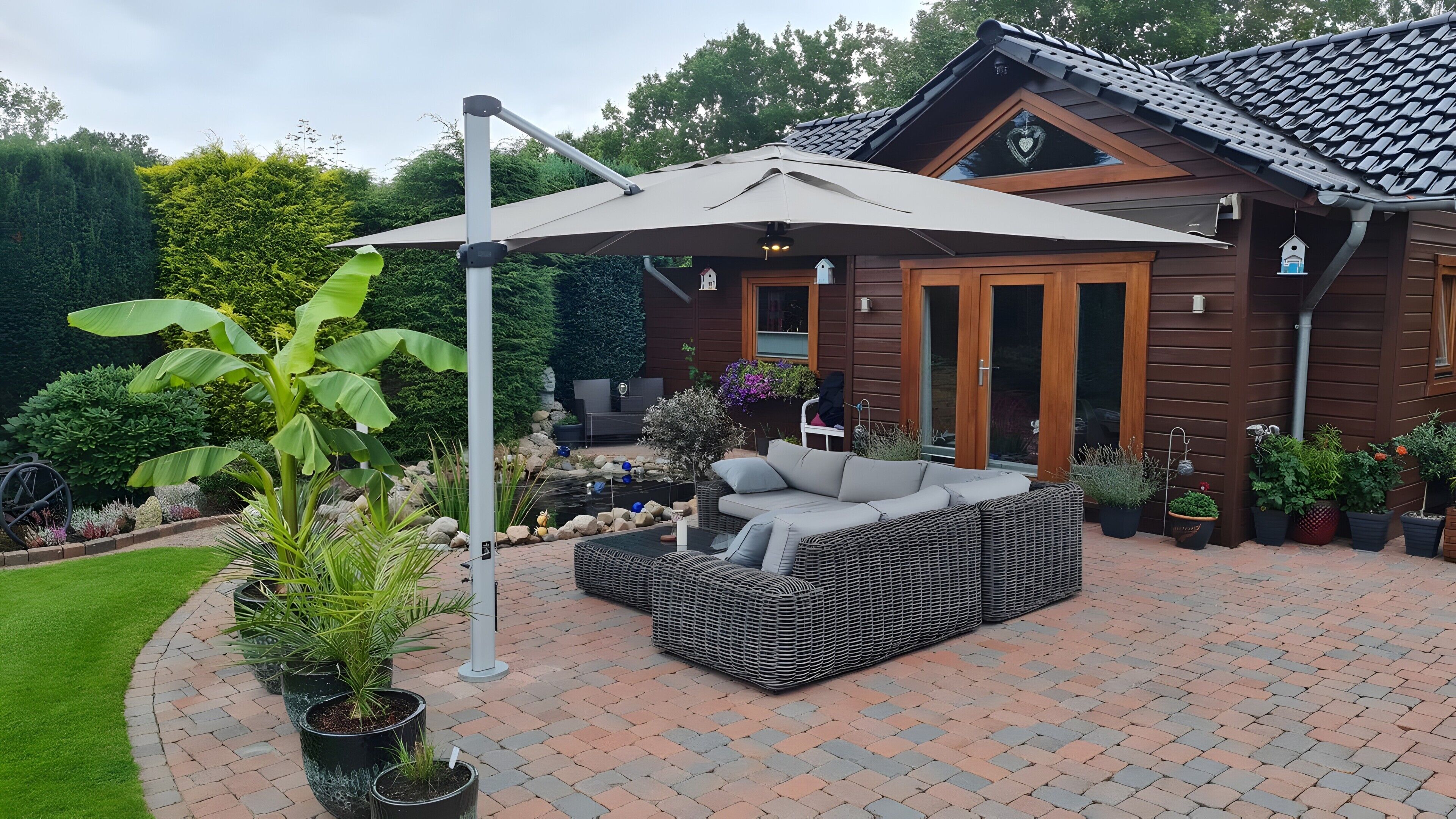 A patio area with a wicker sofa, a pergola, and potted plants.