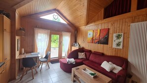 Una cabaña acogedora de madera con comedor, sofá y una pequeña mesa.