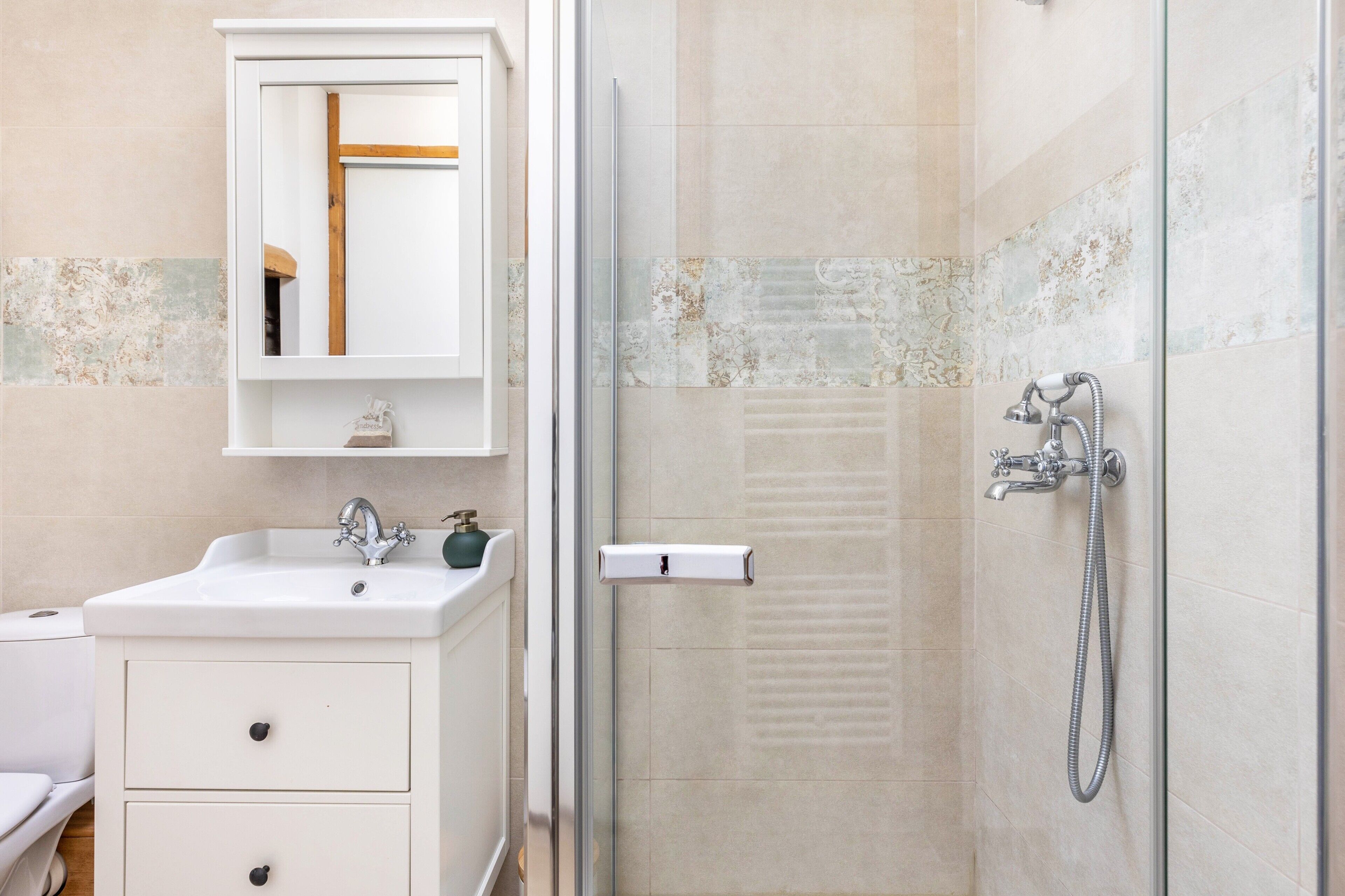 A bathroom with a sink, mirror, and shower.