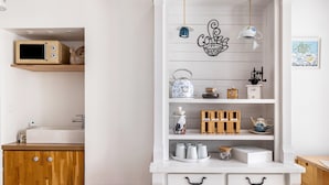 Une cuisine équipée d’un four à micro-ondes, de meubles de rangement en bois, d’un évier et d’un meuble blanc avec des tiroirs.
