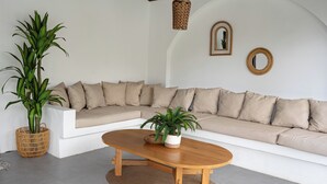 A modern living room with a white sectional sofa, a wooden coffee table, and two potted plants.