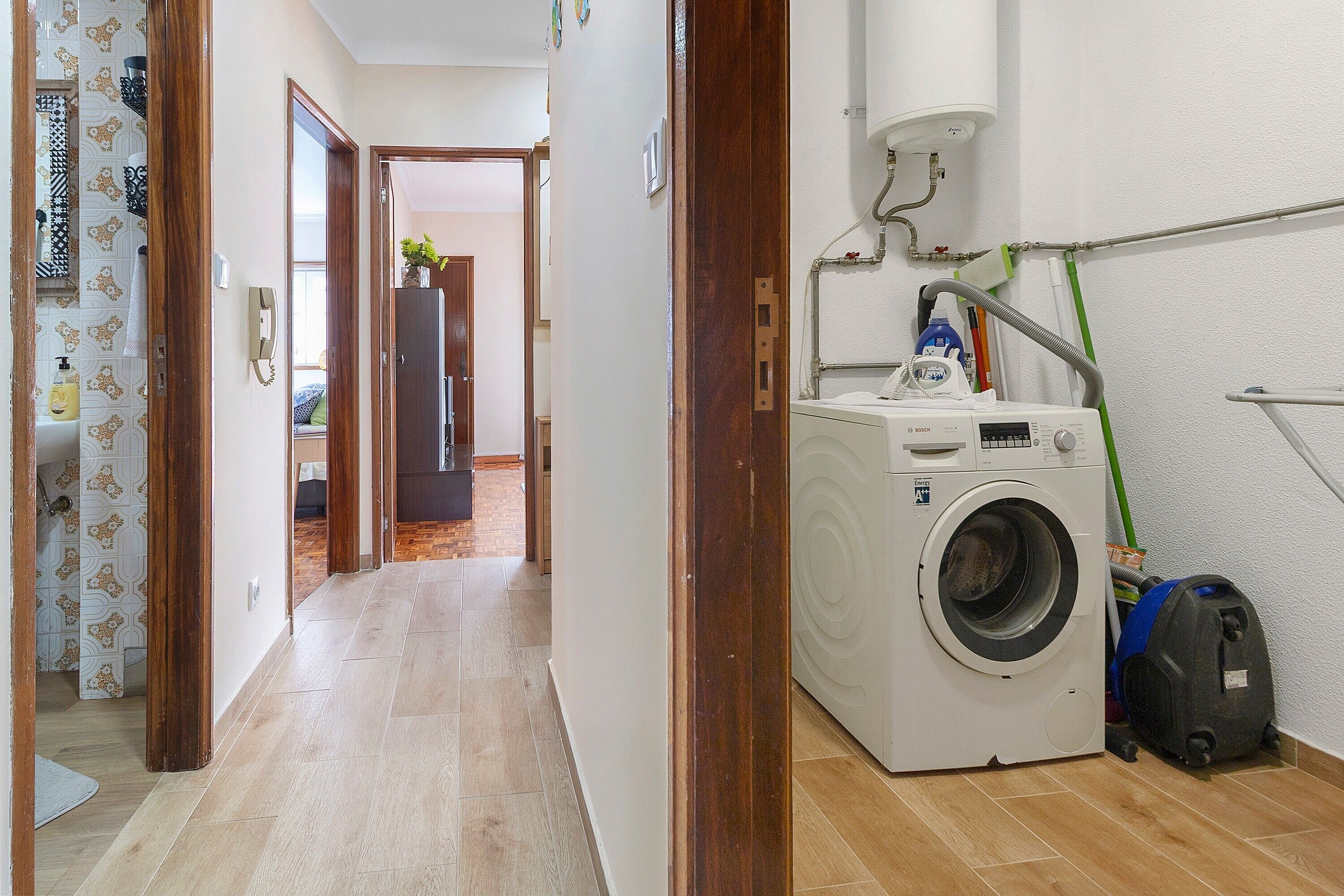 A laundry area with a washing machine, a vacuum cleaner, and a mop.