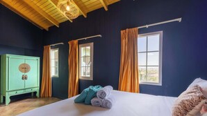 Una camera da letto con un letto, un armadio verde e due finestre con tende.