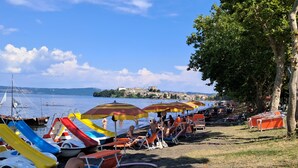A beach with rows of sun loungers and umbrellas, a water slide, and boats. - Cozy apartment in Acquapendente for exploring Tuscia and Tuscany. (Acquapendente)