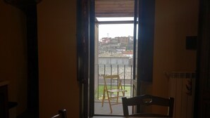 A room with a table and chairs, a window with an open door, and a view of buildings outside. - Cozy apartment in Acquapendente for exploring Tuscia and Tuscany. (Acquapendente)