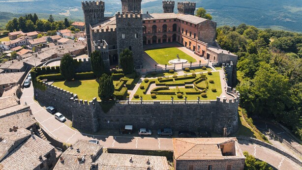 A historic castle with a central courtyard, surrounded by stone walls and featuring a mix of residential and commercial buildings in the background. - Cozy apartment in Acquapendente for exploring Tuscia and Tuscany. (Acquapendente)