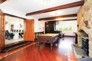 A billiards room with a pool table, a stone fireplace, and a conference room visible through an open door. - Spa Home With Swimming Pool, Hottub, and Sauna (Sheffield)