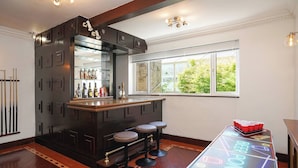 A bar area with stools, a pool table, and a bar stocked with bottles. - Spa Home With Swimming Pool, Hottub, and Sauna (Sheffield)