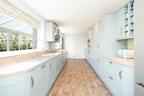 Une cuisine moderne avec des meubles de couleur bleu clair, un plan de travail en bois et un sol carrelé.