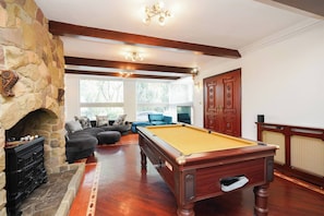 A billiards table in a room with a stone fireplace, a sofa set, and a large wooden door. - Spa Home With Swimming Pool, Hottub, and Sauna (Sheffield)