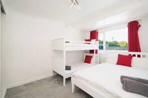 A bedroom with bunk beds, a window with red curtains, and a view of greenery outside. - Spa Home With Swimming Pool, Hottub, and Sauna (Sheffield)