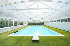 A covered swimming pool with artificial grass, a diving board, and a greenhouse structure. - Spa Home With Swimming Pool, Hottub, and Sauna (Sheffield)