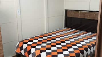 Un dormitorio con colcha a cuadros, cabecera de madera y un cuadro de caballos en la pared.