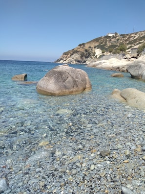 A rocky beach with clear water and large boulders. - Sunset Terrace (Toscana)