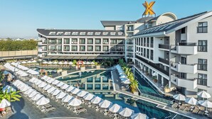 Ein Hotel mit mehreren Etagen, einem Pool und Außenbereichen mit Sitzgelegenheiten.