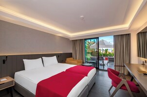 Habitación de hotel con una cama grande, un escritorio, una silla y vistas al exterior.