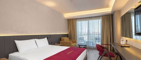 A hotel room with a bed, a desk, a chair, a TV, and a window with curtains.