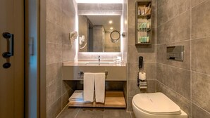 Ein modernes Badezimmer mit großem Spiegel, Waschbecken, Toilette und Handtuchhalter.