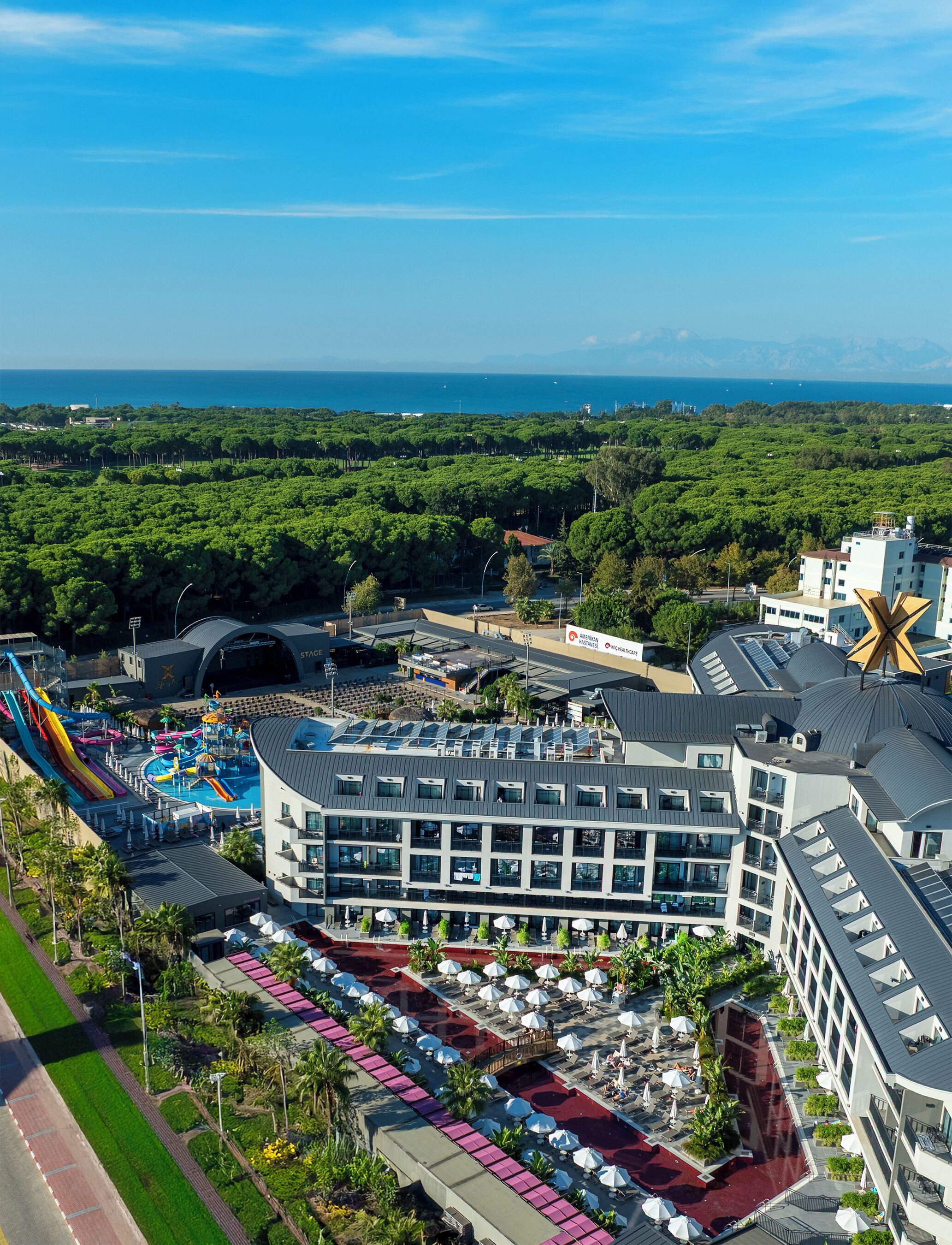 A hotel with a pool area, a water park, and a view of the ocean.