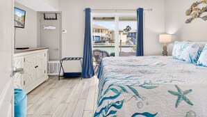Ein Schlafzimmer mit Bett, Fernseher, Kleiderschrank und Blick auf einen Pool sowie Gebäude.