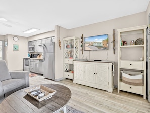 Een ruimtelijk ingerichte leefruimte met een kitchenette, een flatscreen-tv en een zithoek.