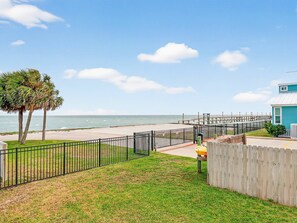 A coastal view with a wooden fence, a paved walkway, and a building with a blue exterior.