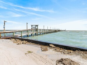 A pier extending into the sea with a small structure at the end.