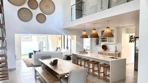 Una cocina moderna con una isla central, taburetes de bar e iluminación colgante.
