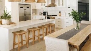 Una cocina moderna con una isla central, taburetes de madera e iluminación colgante.
