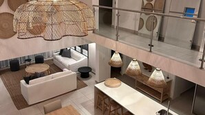 Un interior moderno con un sofá blanco, una mesa redonda de centro y un comedor con una mesa larga y taburetes de bar.