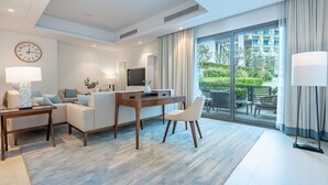 A modern hotel room with a sofa set, a wooden coffee table, a TV, and a large sliding glass door leading to an outdoor area. - Peaceful Villa Bedroom + Assistant Room, Cliffside View (Fujairah)