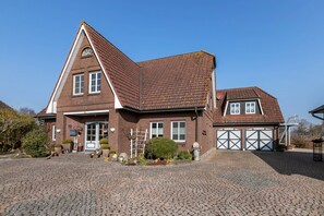 Une maison à deux étages, avec une façade en briques, un toit en pente et une allée.